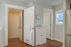 A kitchen with a refrigerator, a clock, and a cabinet.