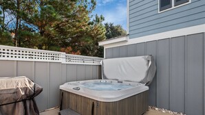 Boblebad med låg, en trappestige og en terrasse med hegn og træer i baggrunden.