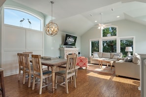 A spacious living area with a dining table, chairs, a sofa, and a television.