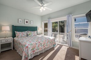 A bedroom with a bed, nightstands, a ceiling fan, and a balcony with curtains. - Salty Breeze: Oceanside, Elevator,Hot Tub, Community Pool Access! (Corolla)
