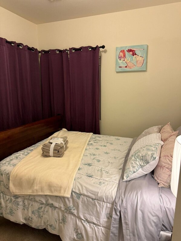 A neatly made bed with a floral duvet, a folded towel, and a decorative pillow. - Desert Haven with Modern Touches – Your Tucson Home Away from Home (Tucson)