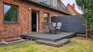 Ein Backsteinhaus mit Balkon, einer Holzterrasse und Sitzgelegenheiten im Freien.