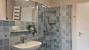 Ein modernes Badezimmer mit Duschkabine aus Glas, Waschbecken und Spiegel.