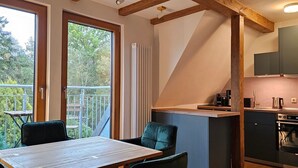 Una cocina con horno integrado y un comedor con mesa y sillas.
