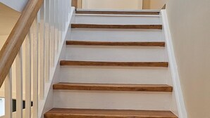 Una escalera con escalones de madera y barandillas blancas que lleva a una puerta.