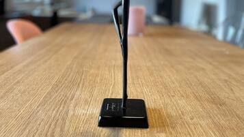 A black, modern, minimalist sculpture on a wooden table in a room with a simple, clean design.
