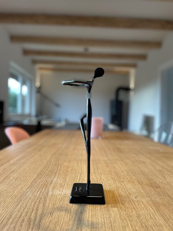 Una escultura negra, moderna y minimalista sobre una mesa de madera en una habitación de diseño sencillo y limpio.