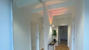 A hallway with wooden flooring, white walls, and a black console table with a potted plant. - Newly renovated vacation home - 4 min. to the beach - large, quiet lot surrounded by nature  (Schashagen)