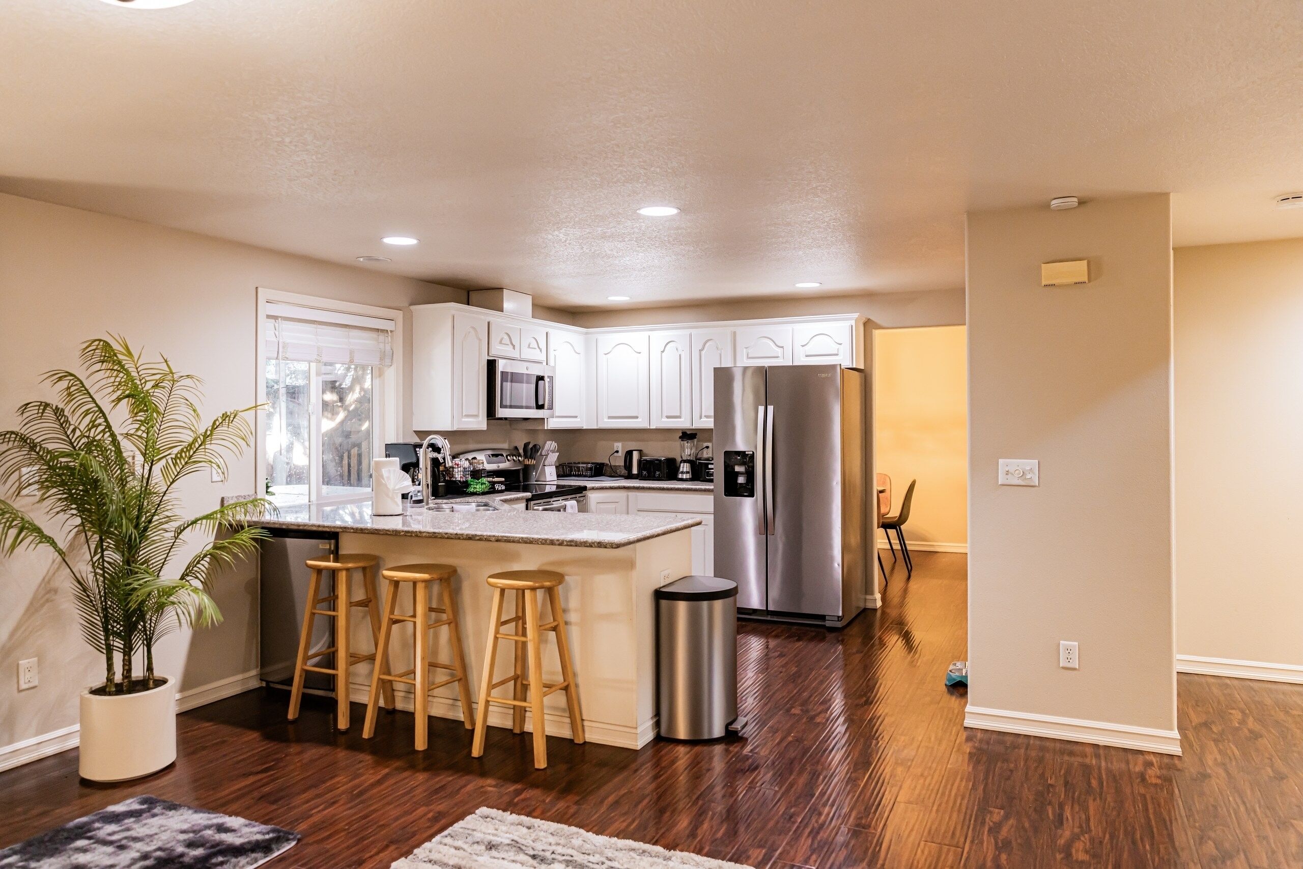 A modern kitchen with white cabinets, stainless steel appliances, and a central island with stools.
