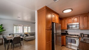 Una cocina moderna con armarios de madera, electrodomésticos de acero inoxidable y un comedor con sofá y mesa.