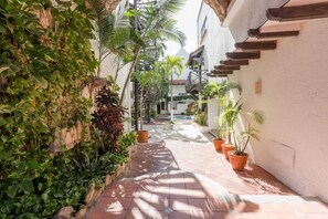 Stroll through a serene courtyard surrounded by lush greenery and potted plants, with a spiral staircase leading to upper levels.