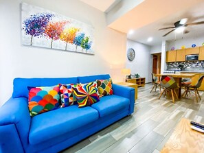 Relax in this stylish living room with a sofa, dining table, and kitchen area.