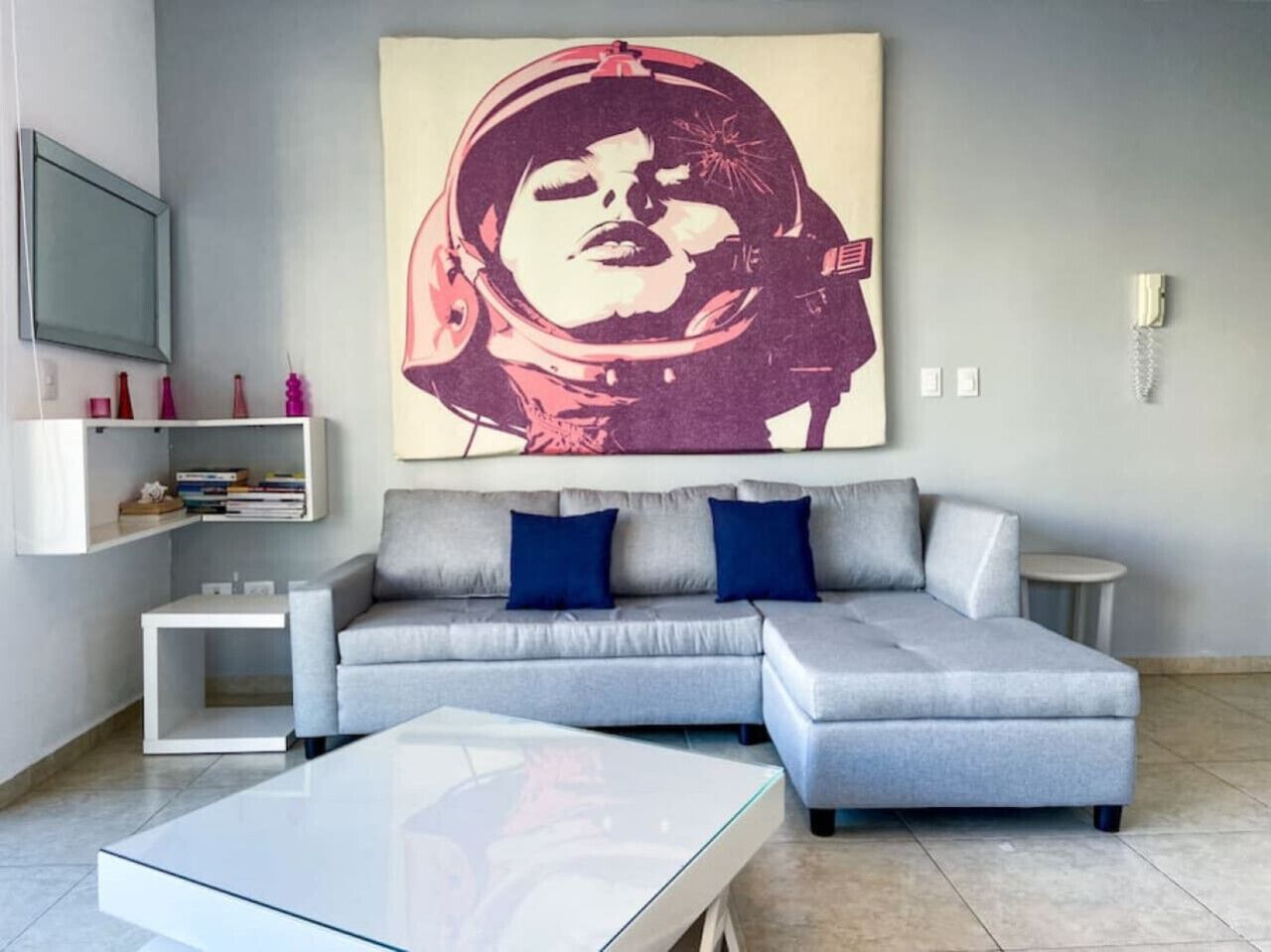 A modern living room with a grey sectional sofa, a glass coffee table, and a large abstract painting on the wall.