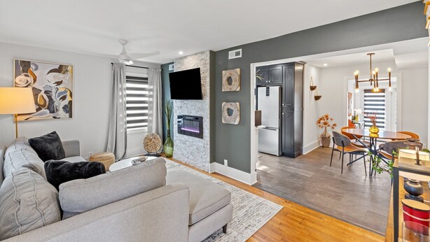 Een moderne woonkamer met een grijze bank, een flatscreen televisie en een open haard.