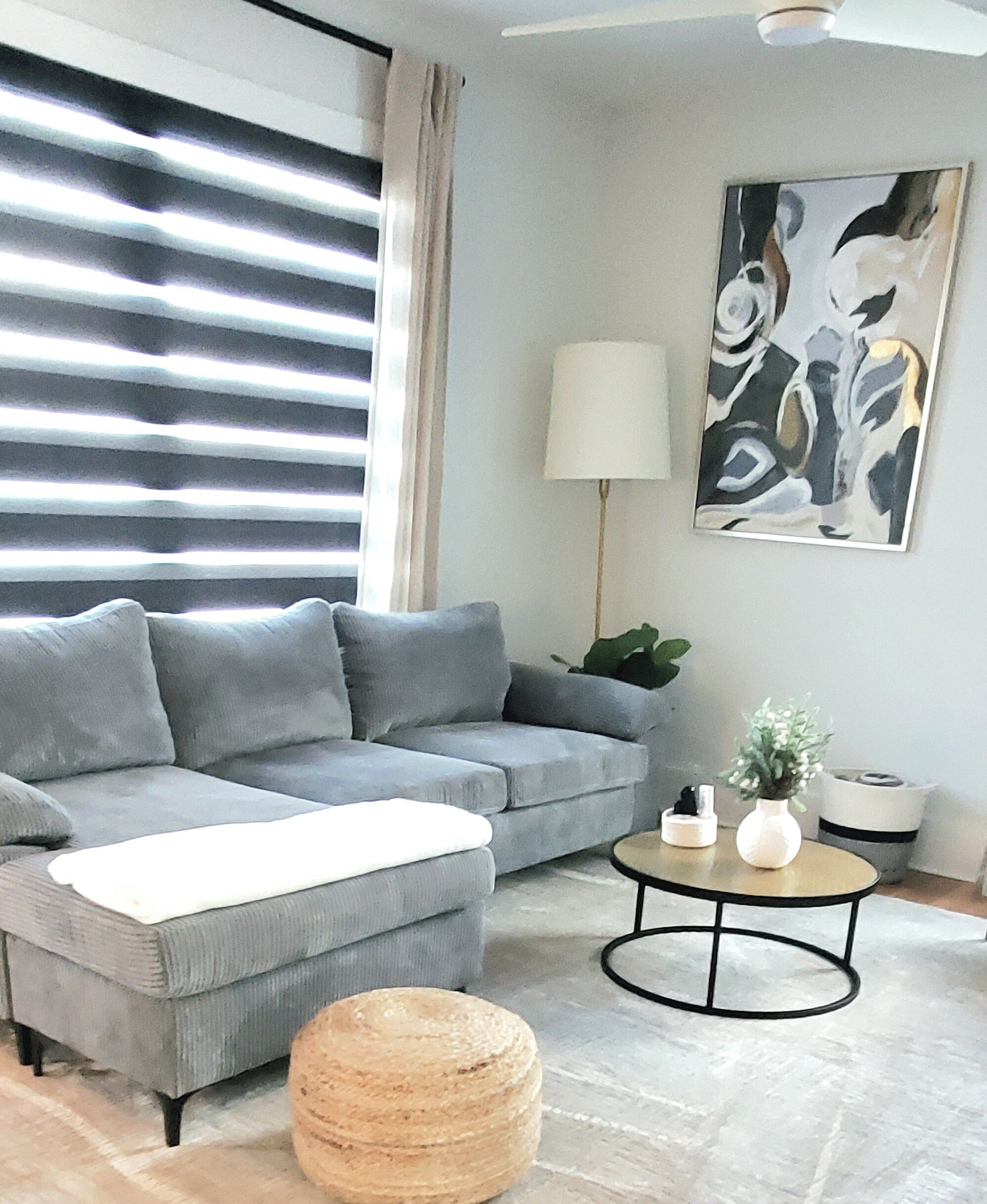 A modern living room with a grey sectional sofa, a round coffee table, and a floor lamp.