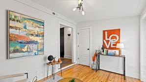 Een moderne woonkamer met een houten vloer, een ronde salontafel, een schilderij en een 'LOVE' bord op de muur.