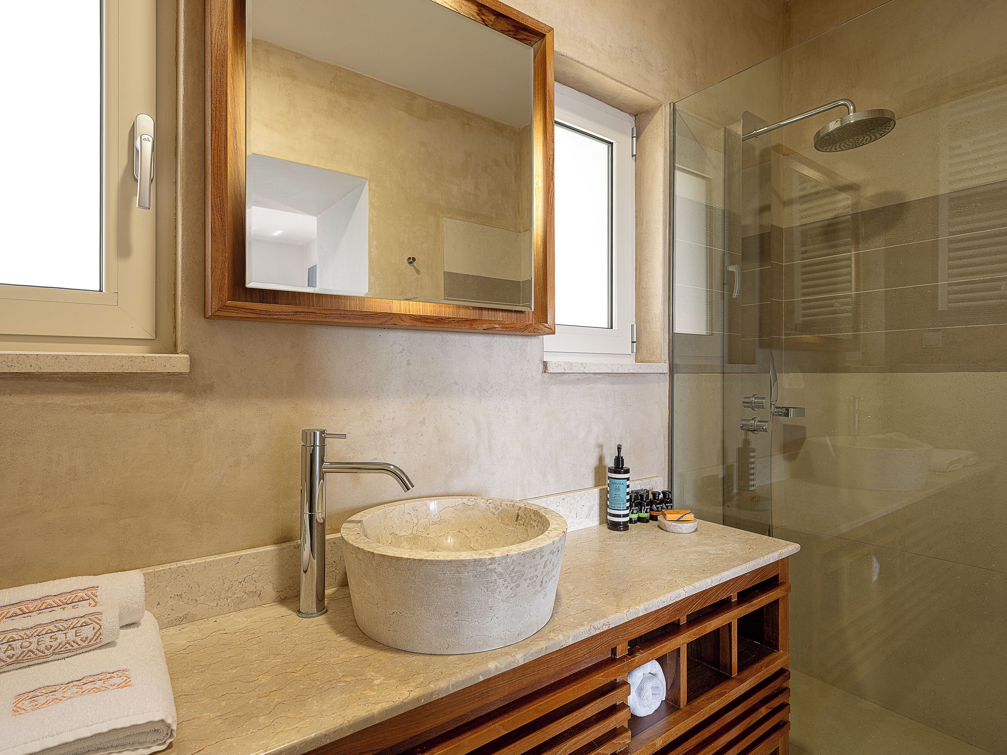 Een badkamer met een grote ronde wastafel, een spiegel en een douche.