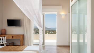 Un dormitorio con cama, escritorio, televisor y balcón con vista al mar.