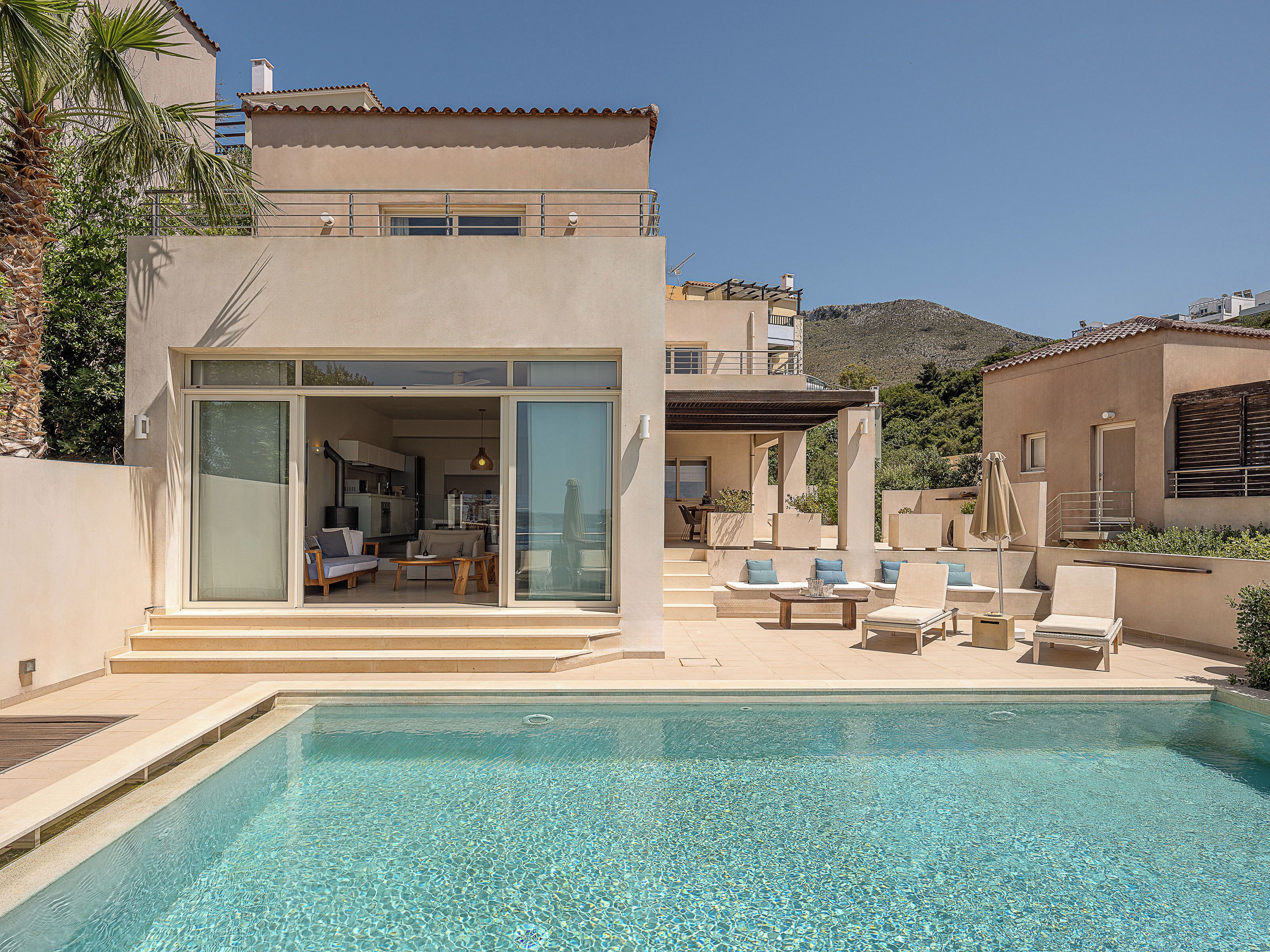 Una villa moderna con piscina, mobiliario de exterior y zona de patio.