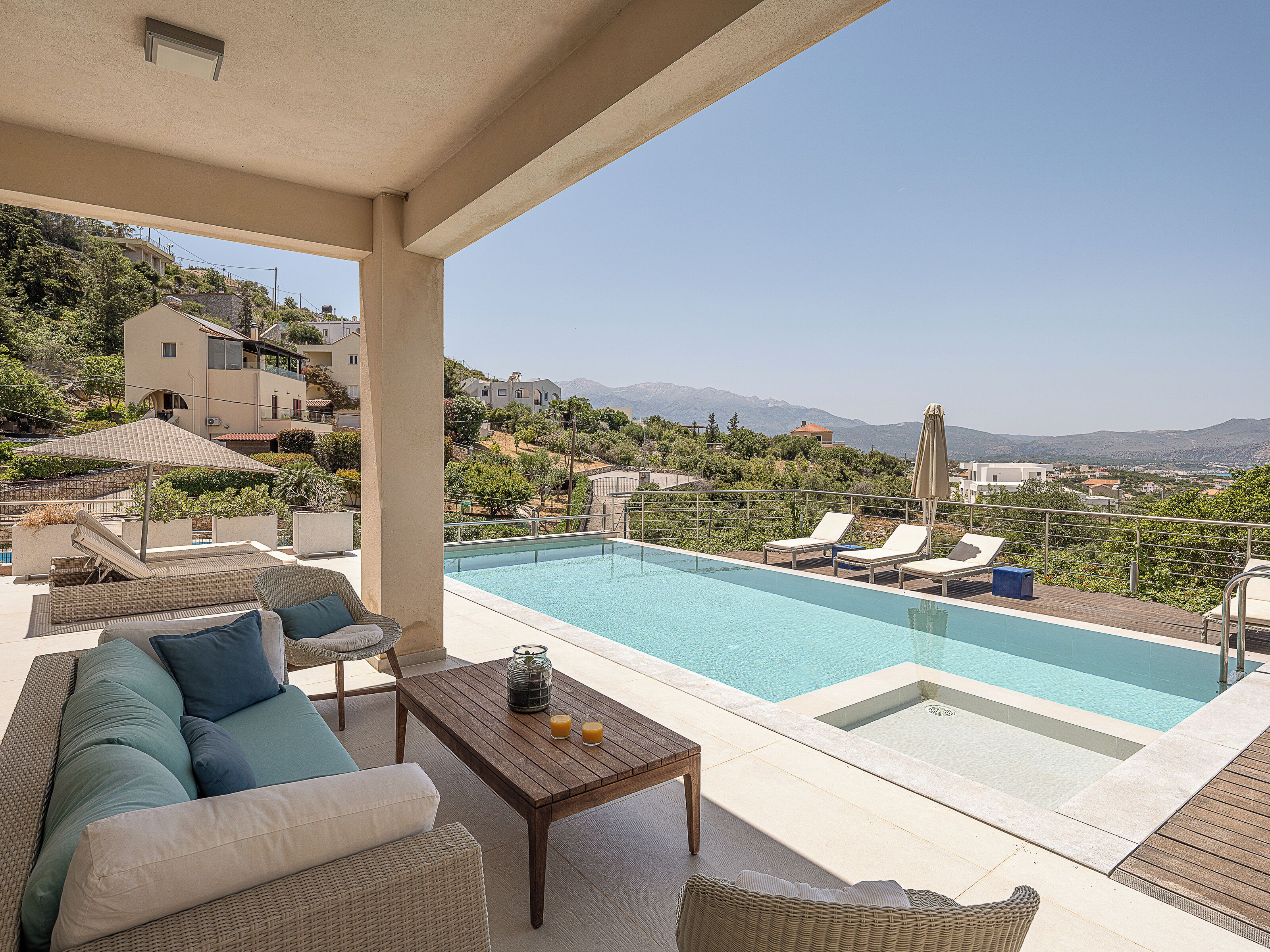 Un espace aménagé au bord de la piscine, avec des chaises longues, une table en bois décorée de bougies et une vue sur le paysage environnant.