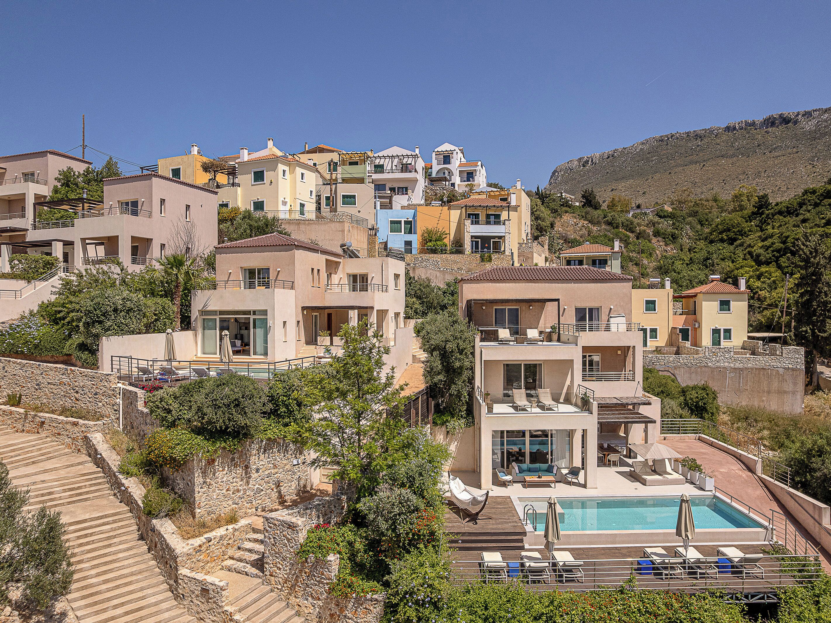 A hillside residential area with modern houses, a swimming pool, and a stone staircase.