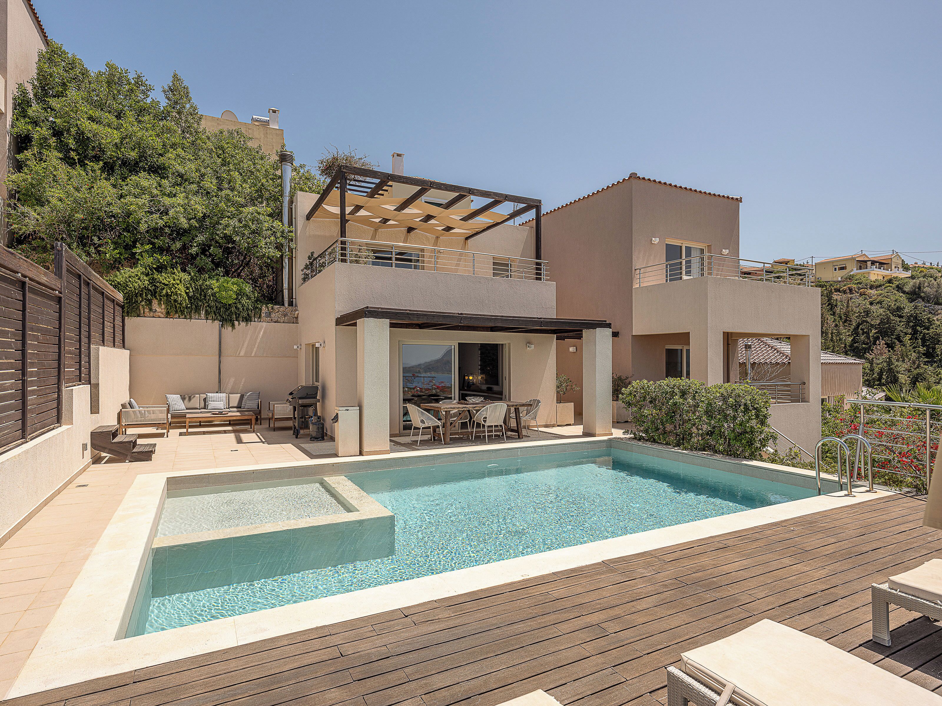 A modern two-story house with a swimming pool, outdoor seating, and a pergola.