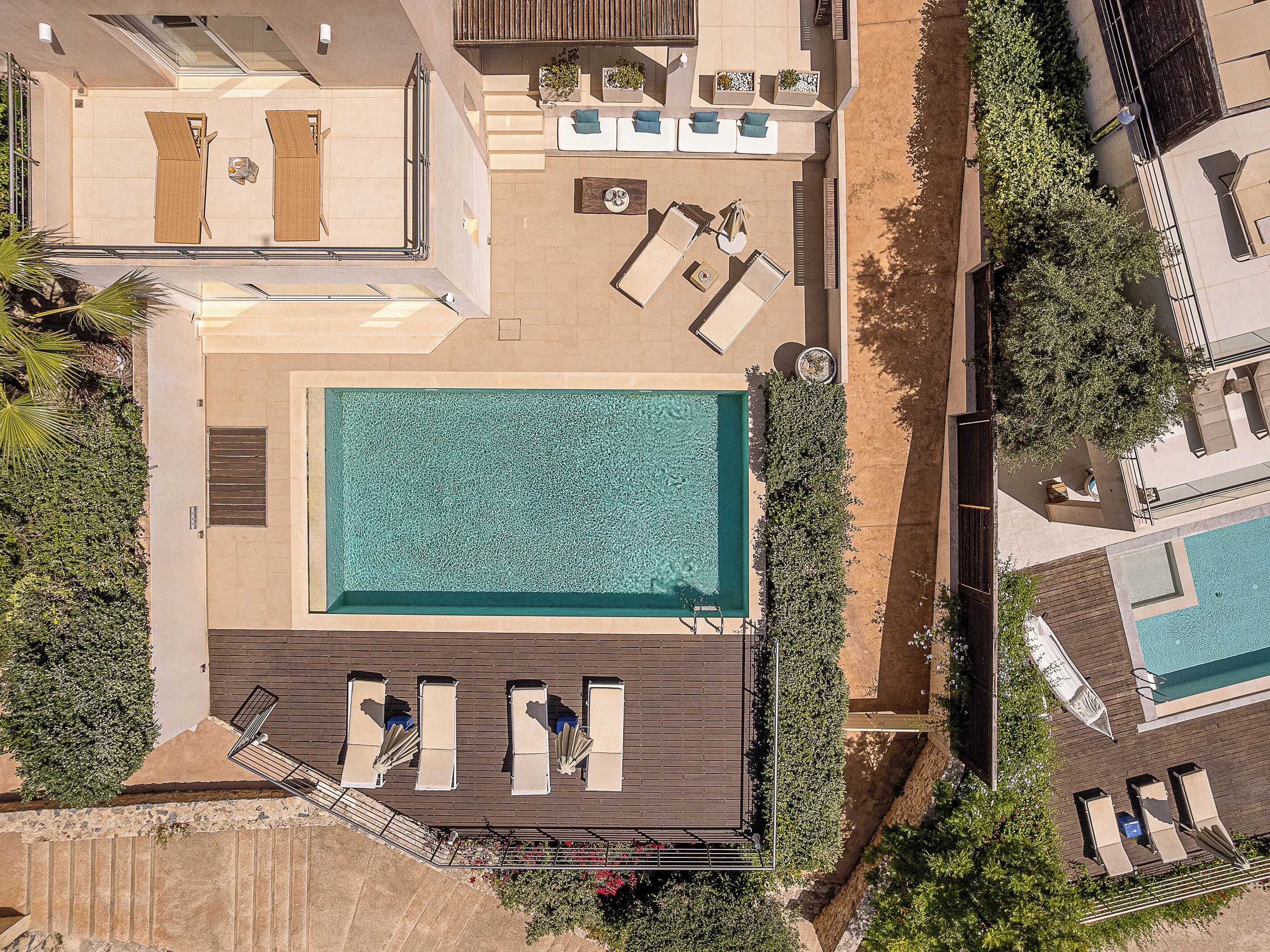 Ein Luftbild eines Resorts mit einem zentralen Schwimmbecken, Liegestühlen und einem kleinen Garten.