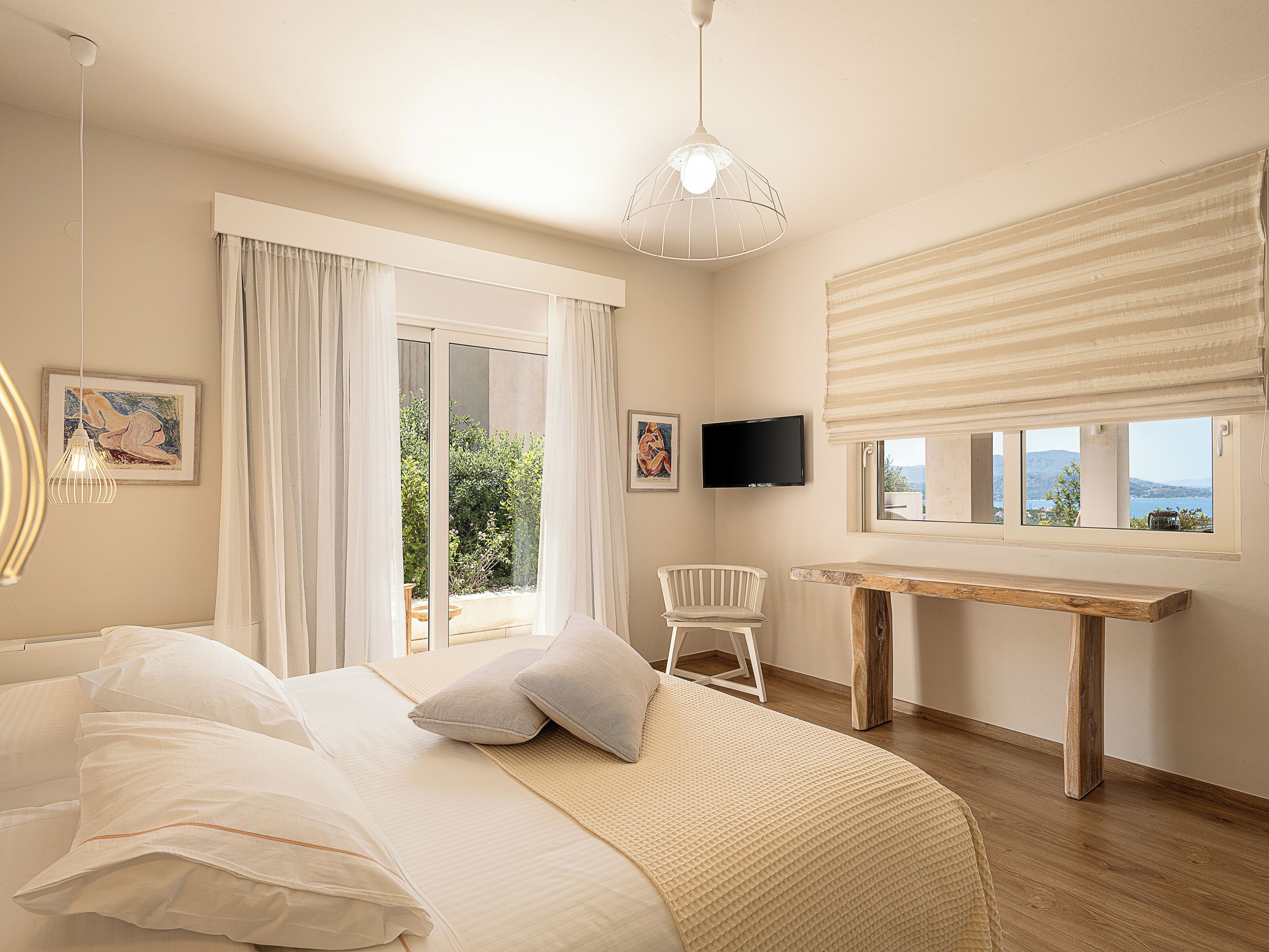 A bedroom with a bed, a desk, a chair, a TV, and a view of the outdoors.