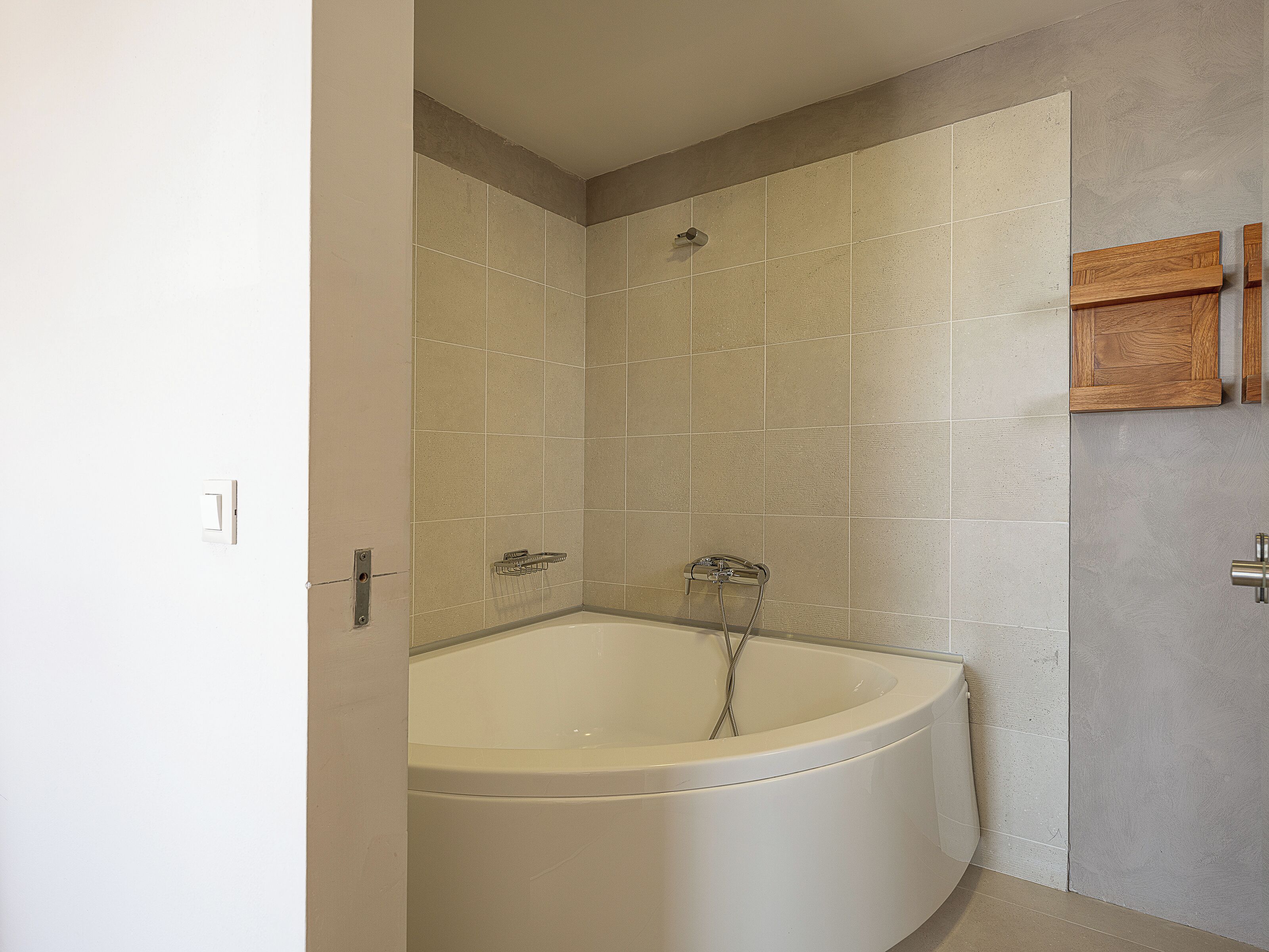 Ein Badezimmer mit freistehender Badewanne, gefliesten Wänden und einem Holzschrank.