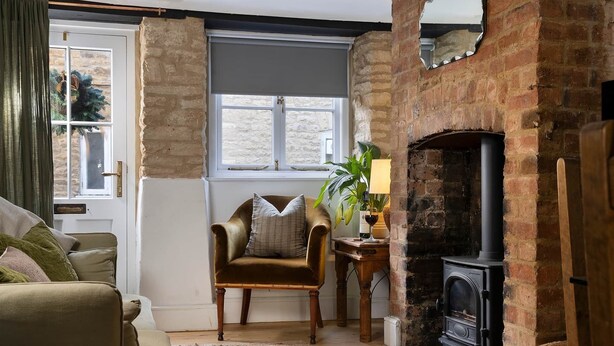 A cozy living room with a brick fireplace, a comfortable armchair, and a sofa. - The Honey Stone Townhouse, Trendy Townhouse in Chipping Norton (Chipping Norton)