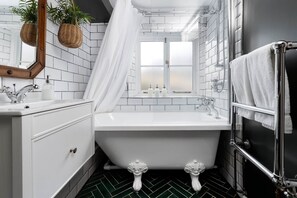 Une salle de bain avec une baignoire blanche, un lavabo blanc et un espace douche.