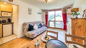 Una habitación acogedora con sofá, mesa de comedor y vistas al exterior.