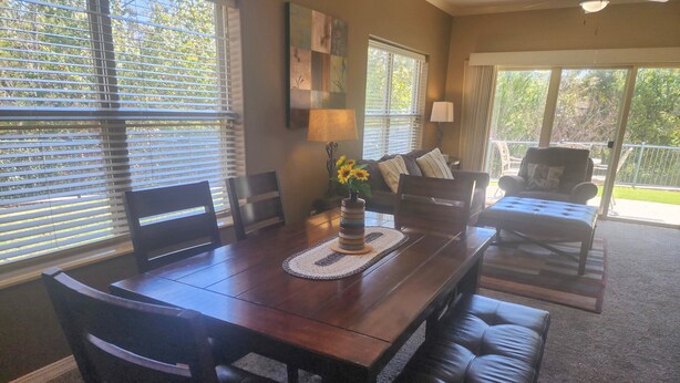 A dining area with a wooden table, chairs, and a bench. There is a vase with flowers on the table. - Majestic Cove | 2BR Branson Condo w/ Table Rock Lake Views (MJ126) (Branson)