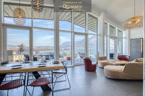 Una habitación amplia con ventanas grandes, comedor y zona de estar con vista a las montañas.