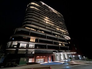 Ein mehrstöckiges Hotel mit modernem Design, das eine markante Eingangshalle und einen Parkbereich aufweist.
