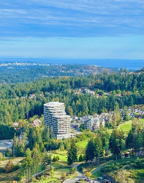 Ein Hochhaus-Hotel mit zahlreichen Balkonen, umgeben von dichtem Wald und einem Golfplatz.