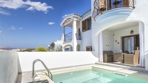 A pool area with lounge chairs and a view of a white building with balconies. - Victoria by Interhome (Budoni)