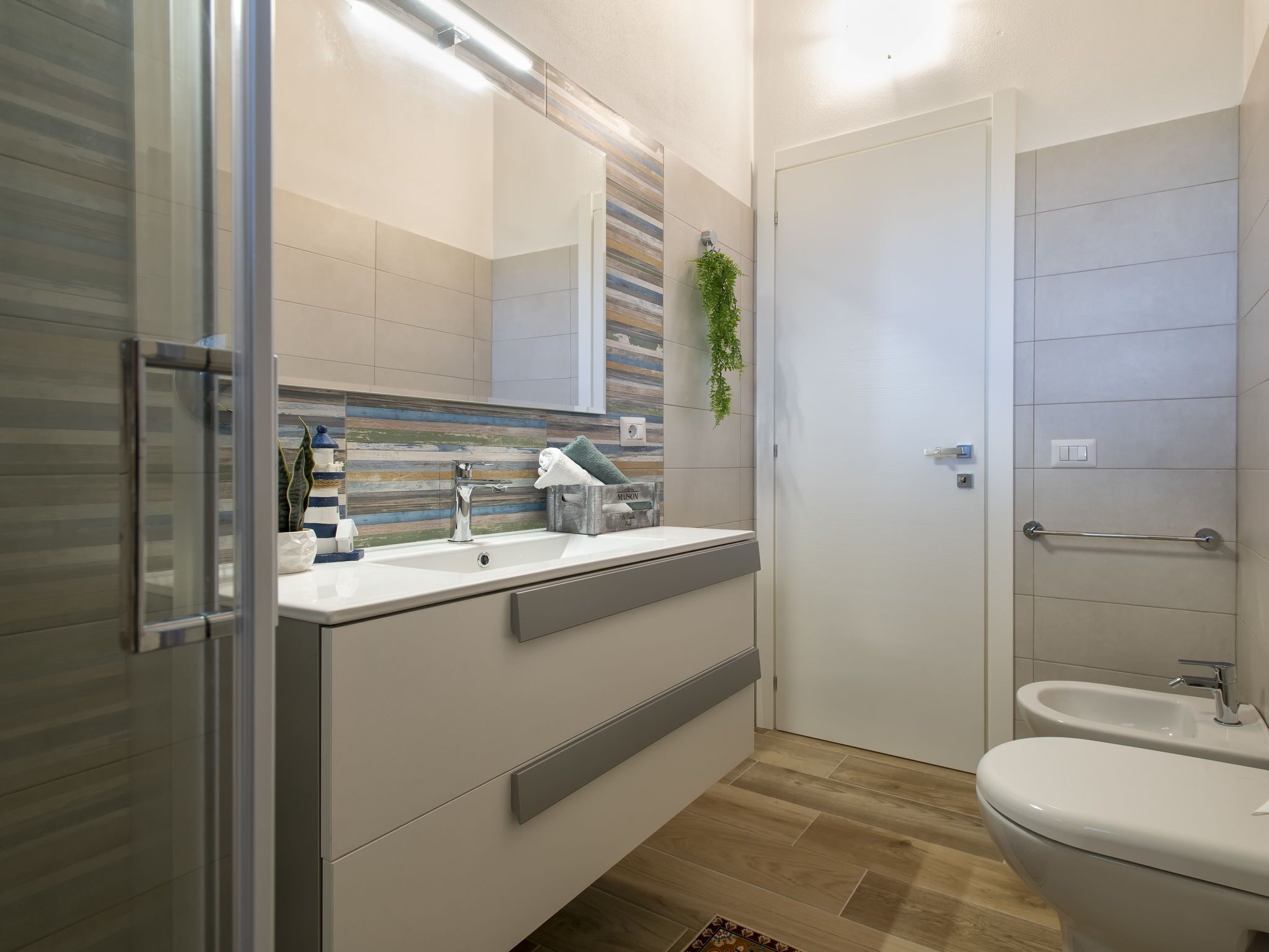 Ein modernes Badezimmer mit einem großen Spiegel, zwei Waschbecken, einer Toilette und einem Bidet.