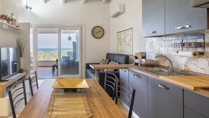 A modern kitchen with a wooden dining table, dark cabinets, and a view to the outdoors. - Stogu di Lusso by Interhome (Valledoria)