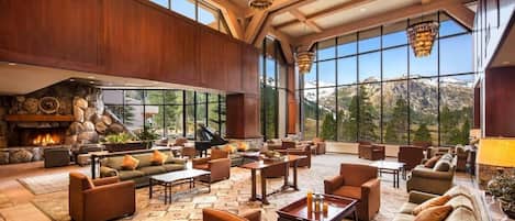 A spacious lobby with a stone fireplace, multiple seating areas, and large windows offering mountain views.
