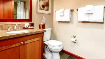 A bathroom with a wooden vanity, a sink, a toilet, and two towel racks.