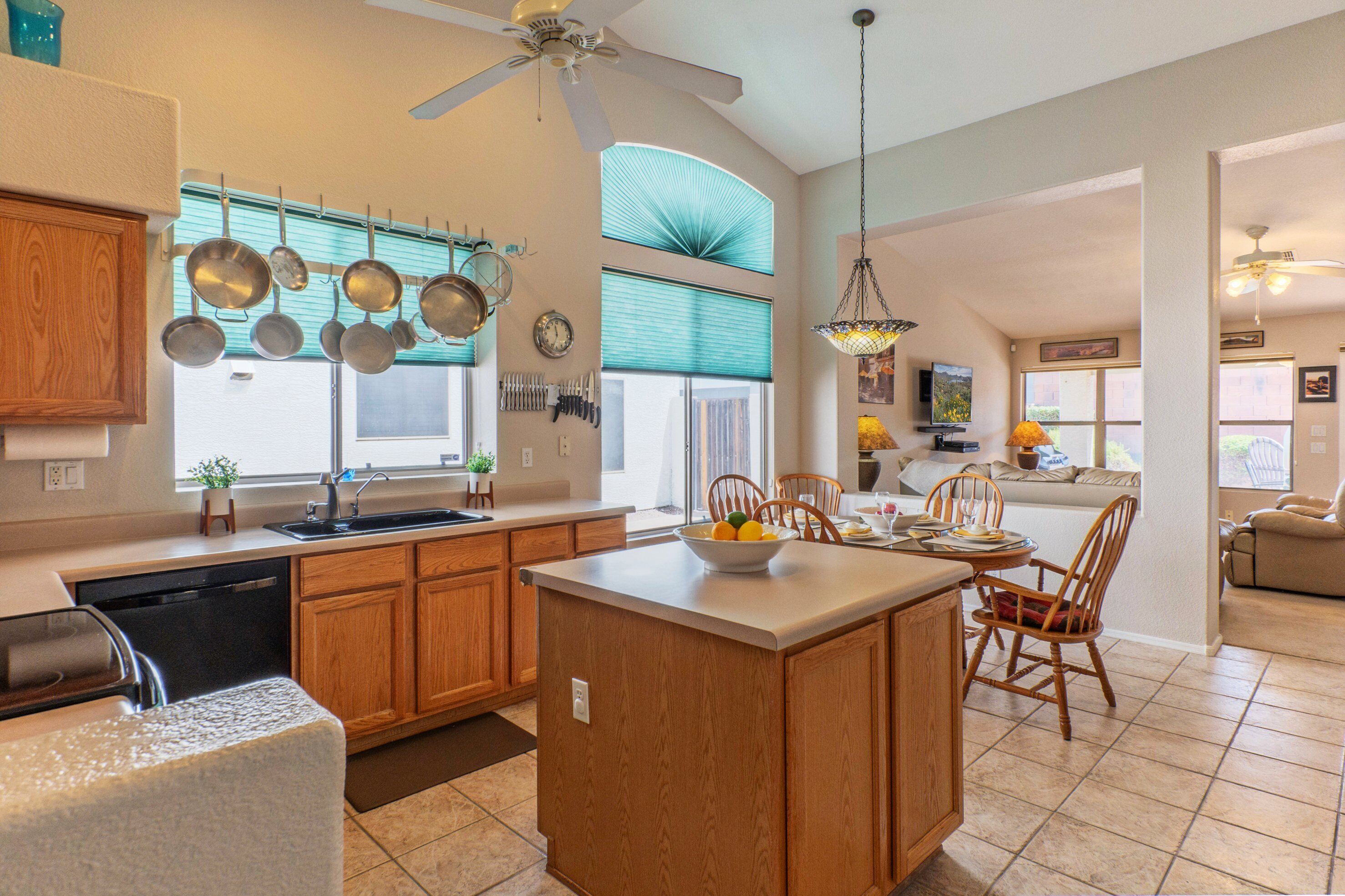 A spacious kitchen with wooden cabinets, a central island, and a dining area with chairs.