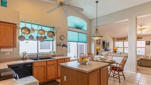 A spacious kitchen with wooden cabinets, a central island, and a dining area with chairs. - Covered Patio, Lava Rock Gas Fire Pit, Near Spring Training, Golf, Hiking & Biking; 30 Day Min (Gilbert)