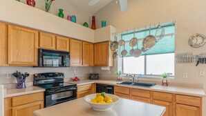 A modern kitchen with wooden cabinets, a black stove, a bowl of lemons, and a window with blinds. - Covered Patio, Lava Rock Gas Fire Pit, Near Spring Training, Golf, Hiking & Biking; 30 Day Min (Gilbert)