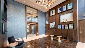 A modern lobby with a marble floor, wooden accents, and a large wall-mounted display.