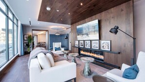 A modern living room with a fireplace, white sofas, and a large TV mounted on a wooden wall.