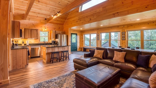 A spacious living area with a large leather sofa and a kitchen with wooden cabinetry and a central island.