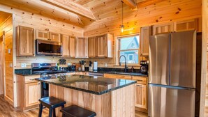 A wooden cabin-style kitchen with a central island, stainless steel appliances, and wooden cabinets.