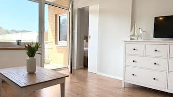 Ein modernes Zimmer mit einem Holztisch, einem weißen Schrank und einem Fernseher.