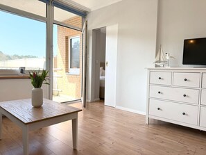 A modern room with a wooden table, a white cabinet, and a television.